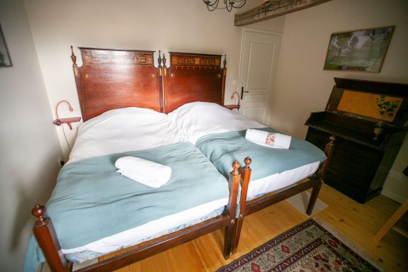 Ein Schlafzimmer mit zwei Betten, weißen Bettdecken und einem Holzschrank im Hintergrund.